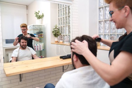 Foto de Un hombre contento observa como su peluquero está diseñado por un profesional. - Imagen libre de derechos