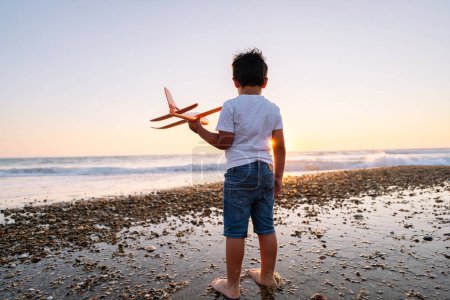 El sueño de un niño vuela en la puesta de sol de una playa de guijarros.