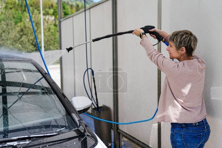 Hohe Konzentration: Frau benutzt Hochdruckwasser im Auto.