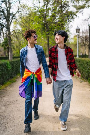 LGBTQ couple, one Latino with flag and one Asian, enjoy a sunny day in the park.