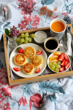 Frühstück im Bett - Quark-Käsekuchen mit schwarzem Kaffee, Orangensaft, saurer Sahne und frischem Obst
