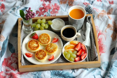 Frühstück im Bett - Quark-Käsekuchen mit schwarzem Kaffee, Orangensaft, saurer Sahne und frischem Obst