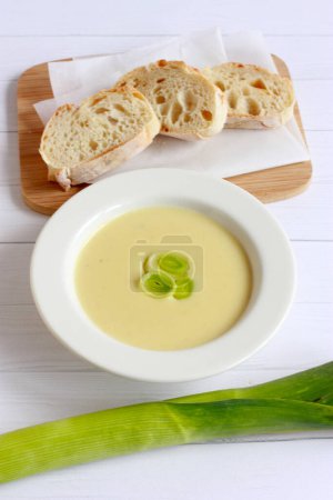 Vichyssoise - french cream soup. Homemade soup puree with potato, leek and cream on white wooden background