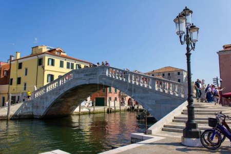Foto de Puente de piedra Ponte di Vigo a través del canal de agua de Vena con coloridos barcos y edificios antiguos en el centro histórico de la ciudad de Chioggia, Véneto, Italia, Europa - Imagen libre de derechos