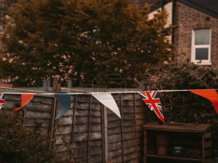 Foto de Banderas de Gran Bretaña ondeando en el viento en el jardín de la casa Inglés, celebración de la coronación . - Imagen libre de derechos