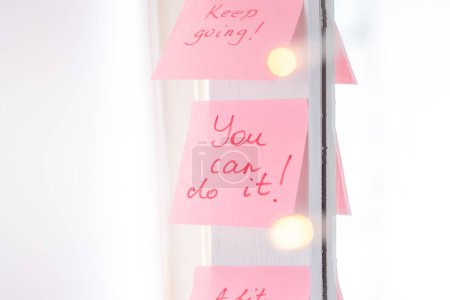 Foto de Citas inspiradoras en pegatina rosa en el espejo, texto de escritura a mano. - Imagen libre de derechos