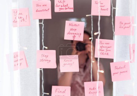 Foto de Citas inspiradoras en pegatina rosa en el espejo, texto de escritura a mano. - Imagen libre de derechos