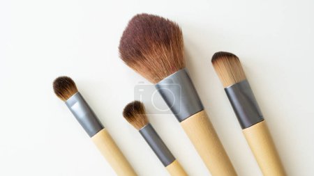 Wooden organic makeup brushes on white backdrop. Eco-friendly, sustainable beauty tools.