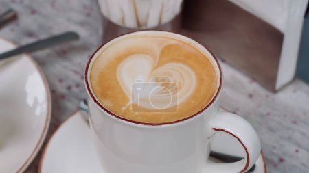 Cremiger Kaffee in einer weißen Tasse auf einem Cafétisch, perfekt für ein friedliches Frühstück...