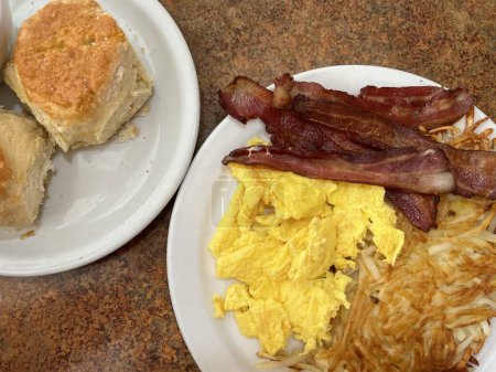 Téléchargez les photos : Petit déjeuner américain traditionnel dans un restaurant de restaurant en Californie - bacon, œufs, pommes de terre, biscuits et sauce. - en image libre de droit