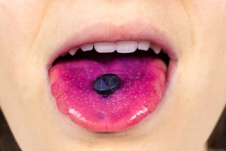 Téléchargez les photos : Une personne montre une pilule indicateur sur sa langue pour déterminer la plaque - en image libre de droit