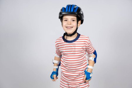 Photo for A happy 5-year-old boy in a protective helmet, elbow pads and gloves has fun. - Royalty Free Image