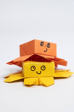 Foto de Dos lindos pulpos de origami amarillo y naranja sobre un fondo blanco, figuras de animales de papel. - Imagen libre de derechos