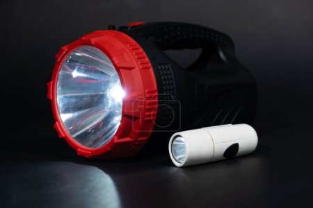 Foto de Dos linternas - bolsillo y linterna linterna brillan en un lugar de fondo negro para texto - Imagen libre de derechos