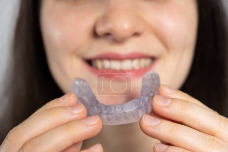 Photo for A woman holds dental mouthguard, splint for the treatment of dysfunction of the temporomandibular joints, bruxism, malocclusion, to relax the muscles of the jaw - Royalty Free Image