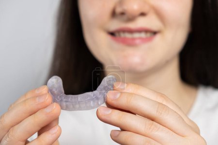 Photo for A woman holds dental mouthguard, splint for the treatment of dysfunction of the temporomandibular joints, bruxism, malocclusion, to relax the muscles of the jaw - Royalty Free Image