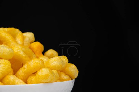 Deliciosos chips de maíz crujientes con especias sobre un fondo negro, lugar para el texto.