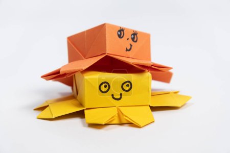 Foto de Dos lindos pulpos de origami amarillo y naranja sobre un fondo blanco, figuras de animales de papel. - Imagen libre de derechos