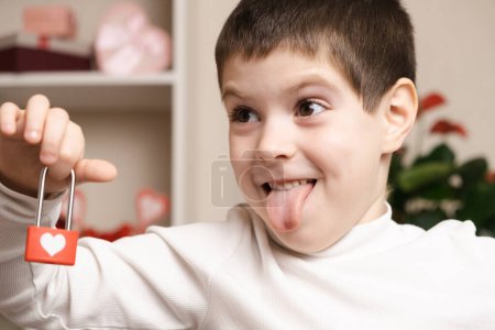 Téléchargez les photos : Saint-Valentin et les enfants. drôle 5 ou 6 année vieux garçon garde une serrure avec coeur et montre sa langue. - en image libre de droit