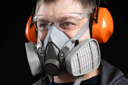 Foto de Retrato de un hombre con un respirador y auriculares protectores que cancelan el ruido orejeras. - Imagen libre de derechos