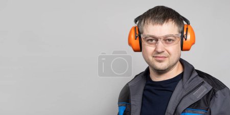 Foto de Un hombre con orejeras, gafas y monos sobre un fondo blanco - Imagen libre de derechos
