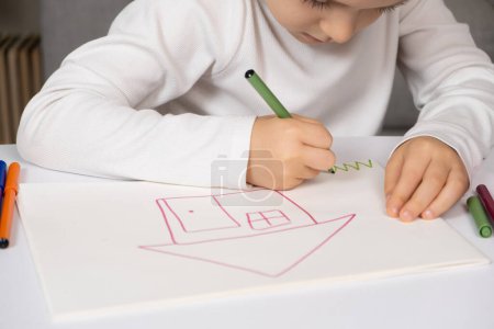 Téléchargez les photos : Petit dessin d'enfant avec feutre stylos une maison avec de l'herbe dans un carnet de croquis - en image libre de droit