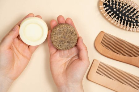 Solid shampoo and conditioner for hair in the hands. Natural cosmetics without plastic, top view on beige background