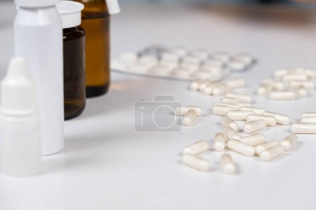 Téléchargez les photos : Beaucoup de capsules blanches sont dispersées sur la table. Concept de médicament, pharmacie. Place pour le texte. - en image libre de droit