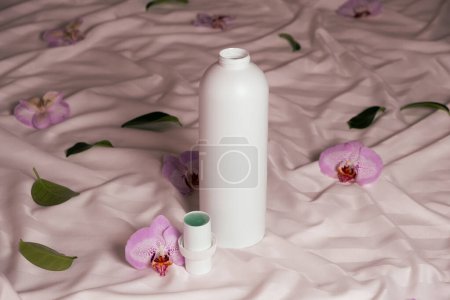 Ecological laundry detergent among orchid flowers on bed linen.