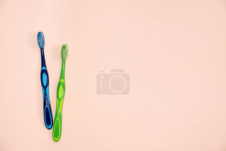 Two toothbrushes on a beige background, top view, space for text