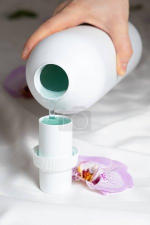 The process of pouring natural eco gel liquid laundry detergent from the bottle into the cap.