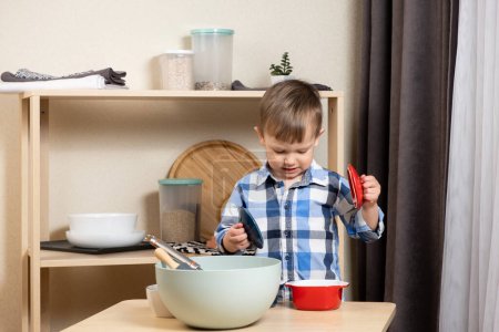 Ein zweijähriger Junge kocht in der Küche und macht Teig. Kochen und Kinder.