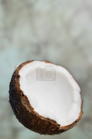 Eine halbe reife Kokosnuss auf grauem, ungleichmäßigem Hintergrund