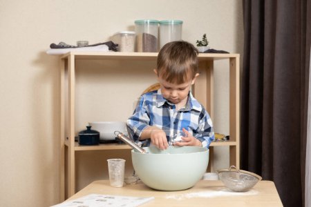 Cute toddler making cookie dough. Toddlers in the kitchen
