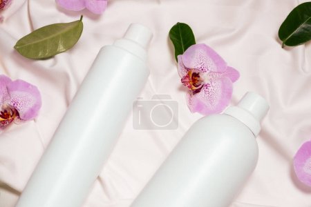 Flüssigwaschmittel und Weichspüler auf Bettwäsche, Orchideenblüten, Draufsicht.