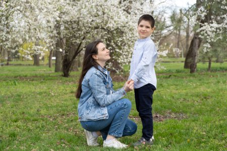 Mom and six-year-old son in blooming garden in spring