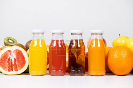 Foto de Diferentes tipos de zumos de frutas: naranja, pomelo, manzana y multifruta en botellas de vidrio - Imagen libre de derechos
