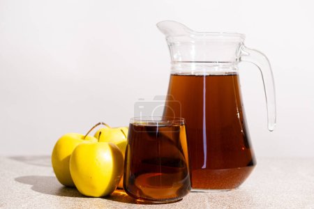 Apple juice in a glass and jug on a white background.