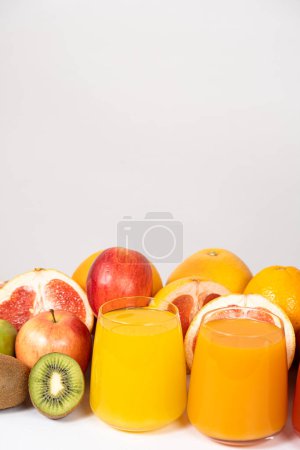 Foto de Zumos de naranja y multifruta en vasos sobre fondo blanco con espacio para texto. - Imagen libre de derechos