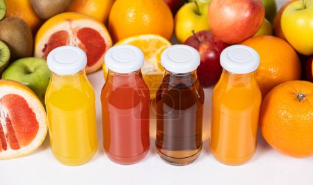 Foto de Diferentes tipos de zumos de frutas: naranja, pomelo, manzana y multifruta en botellas de vidrio - Imagen libre de derechos