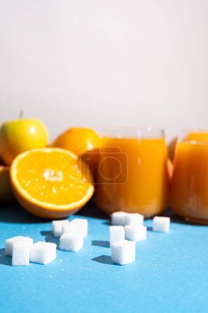 Foto de Contenido de azúcar en los zumos de frutas. Cubos de azúcar y vasos de jugo multifruta - Imagen libre de derechos