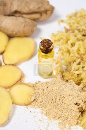Natural ginger oil in glass bottle among ginger roots.