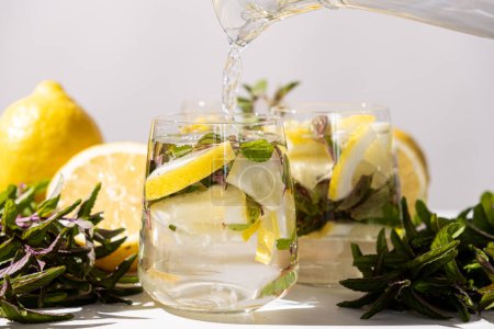 Lemon water with mint pouring into glass