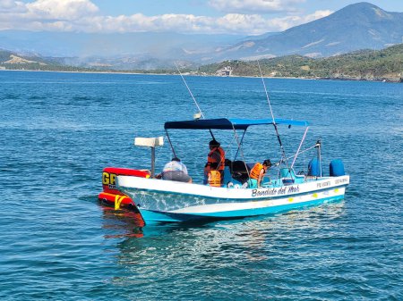 Foto de Explora la tranquila belleza del puerto Vicente Guerrero con un pequeño barco turístico enmarcado por majestuosas montañas - Imagen libre de derechos