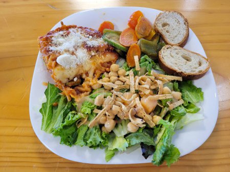Köstliche Lasagne und frischer Salat auf einem Holztisch, Restaurant