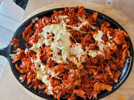 Mouthwatering Al Pastor meat covered in melted cheese, served hot in a skillet