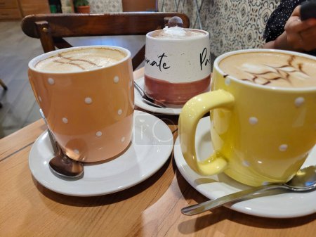 Une sélection de cappuccinos et lattes artisanaux dans des tasses à pois colorés sur une table de café
