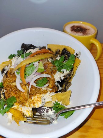 Vertical Perfectly cooked sunny-side-up egg atop spicy chilaquiles, drizzled with crema and sprinkled with sesame seeds