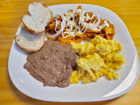 Hearty plate of chilaquiles with scrambled eggs and a side of beans, breakfast food