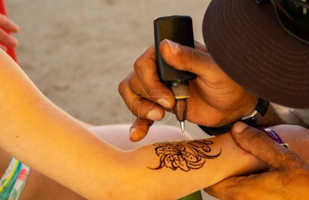 Photo for Tattoo artist doing henna tattoo on a little girl's arm. - Royalty Free Image